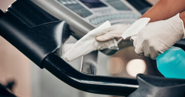 Hands, spray bottle and covid cleaning in gym for healthcare compliance, medical safety and global .